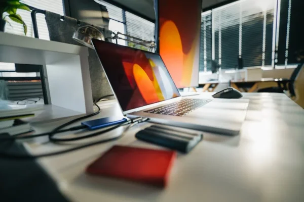 A modern workspace featuring a laptop, external drives, and office equipment on a desk.