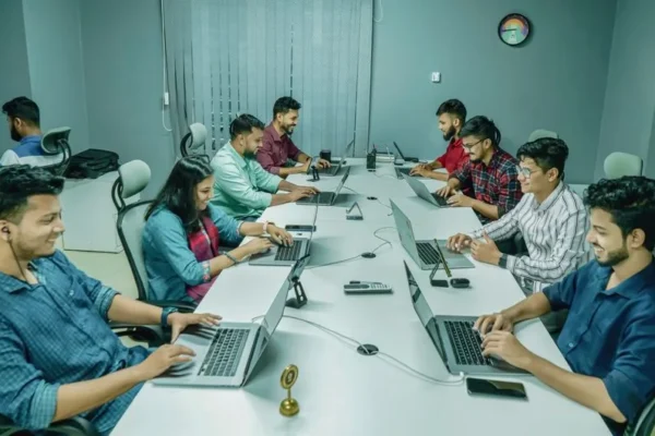 Group of professionals collaborating in a modern office setting on laptops and digital devices.
